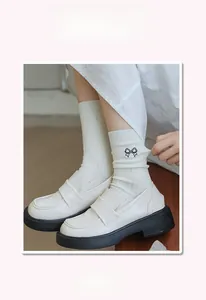 Detailed view of white ribbed socks featuring black embroidered bows and thick-sole loafers