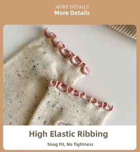 Macro detail of elastic pink ruffled cuff on cream knit socks with colorful yarn specks
