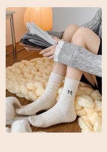 Detail of cotton crew socks featuring embroidered black bows and vertical ribbed texture
