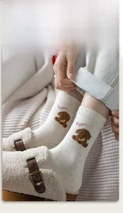 Macro shot of off-white socks featuring brown teddy bear embroidery and elastic rib cuff