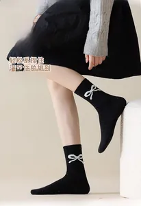Detail of black knit crew socks with colorful flecks and a white bow pattern accent