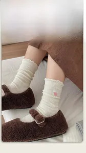 Détail de chaussettes en maille côtelée crème avec broderie cœur rose et bordure