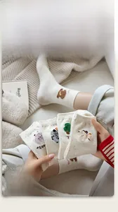 Close-up of beige knit socks with colorful polka dots and cute 3D bear embroidery detail