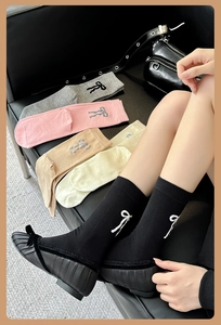 Gros plan de chaussettes en coton mi-mollet avec délicats nœuds brodés en velours