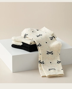 Detailed knit texture of mid-calf cotton socks with bow patterns and speckled yarn dots