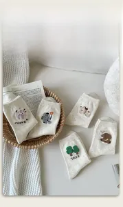 Detail of five pairs of speckled cotton mid-tube socks with cute plush animal embroidery