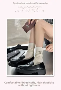 Detail view of ribbed cotton socks featuring sparkling rhinestone bow accessories in neutral colors