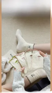 Close-up of cream knit mid-calf socks with rainbow speckles and bow embroidery detail