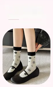 Detail of white cotton crew socks with black rose pattern and soft elastic rib cuffs