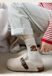 Detail of white cotton socks with colorful flecks, bear print, and cozy faux fur clogs
