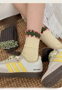 Detail of ruffled beige cotton socks featuring green and pink wavy knit cuffs