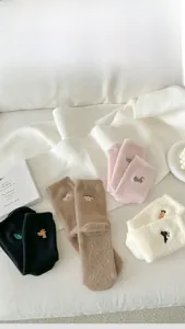 Detail of four pairs of winter wool socks with cute animal embroidery on a cozy blanket