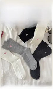 Vue à plat de chaussettes en coton côtelé avec broderie cœur en blanc, gris et noir
