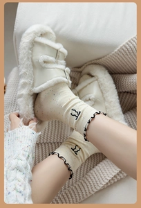 Detail of cream cable knit socks with colorful specks and black ruffled edges