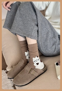 Detail of brown cotton socks with cartoon bear pattern worn with suede clogs shoes