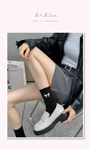 Detail of black mid-calf socks with rhinestone bow and white platform loafers