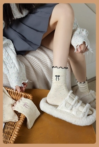 Detail of cream calf socks with colorful dots, bow embroidery and wavy black edges