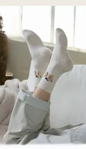 Close-up of off-white socks with cute brown bear embroidery and colorful flecks texture