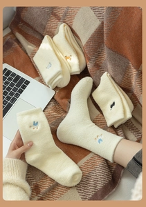 Close-up of thick plush socks with cute animal embroidery on warm ivory coral fleece