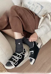 Gros plan de chaussettes en tricot brodées de cœurs et sandales à boucles avec fourrure