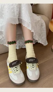 Close-up of retro cream leather sneakers with yellow stripes and pink ruffled cotton socks