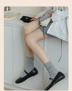 Detail of ribbed knit cotton socks featuring delicate embroidered bow on the side