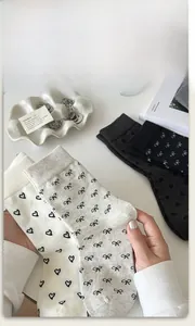 Detail of cotton crew socks featuring black heart and bow patterns in a lifestyle setting