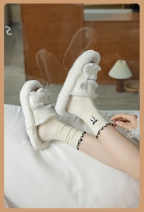 Detail of white plush slippers with dual metal buckles worn with lace dot socks