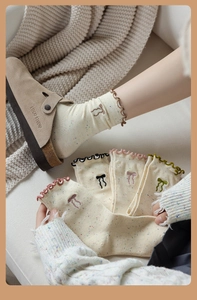 Detailed close-up of warm beige knit socks with colorful specks and bow embroidery