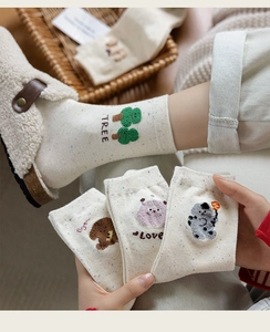 Detail of cozy winter socks featuring cute 3D cartoon embroidery and colorful flecked yarn