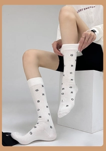 Close-up of white calf socks featuring black letter print pattern on cotton fabric