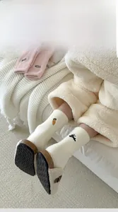 Close-up of fluffy winter socks with cute rabbit and carrot embroidery on plush fabric