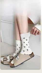 White cotton crew socks featuring black heart jacquard patterns and elastic ribbed cuffs
