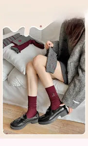 Detail of red knitted socks with bow embroidery and grey heart pattern crew socks