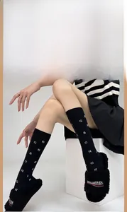 Detail of black cotton calf socks with white letters paired with fuzzy slippers