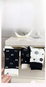 Close-up of white and black mid-calf socks with floral jacquard and bow details