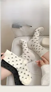 Detail of cream bow pattern and dark grey heart motif socks on soft ribbed cotton