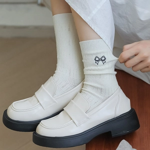 White knit crew socks with embroidered black bow detail paired with chunky loafers