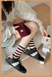 Detail of red and white striped socks with delicate bow embroidery and sneakers