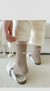 Detail of winter thermal socks with dog embroidery paired with plush white slippers