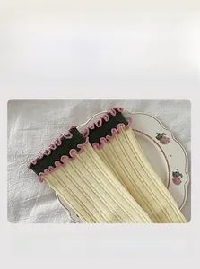 Close-up of ribbed cotton socks with green and pink ruffled edge and elastic top
