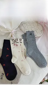 Dettaglio calzini femminili con ricamo a fiocco e bordi arricciati in stile vintage