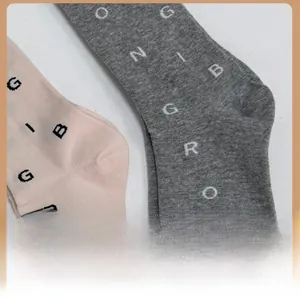 Close-up of pink and grey knitted calf socks showing heel detail and letter patterns