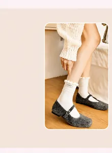 Detailed view of cream-white ribbed socks with sweet ruffled edges and branded fabric label