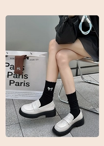 Detail of black mid-calf socks featuring a rhinestone bow and glossy platform loafers