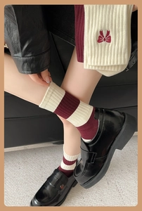 Detail of red and white striped knit socks featuring sweet bow embroidery and ribbed texture
