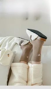 Detail of warm brown wool socks with cute embroidery and white plush slipper clogs
