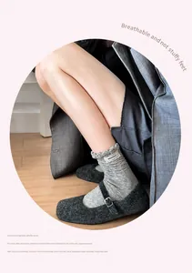 Detail of grey ruffled cotton socks with wavy edges and brand tag paired with Mary Jane shoes