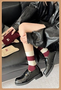 Close-up of vintage burgundy striped socks with embroidered bow details and warm knit texture