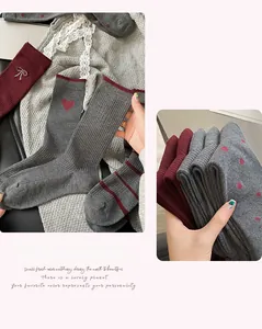Detail of grey and burgundy ribbed mid-tube socks with red heart embroidery and bow accents